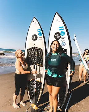 Joss Alabi sonriendo con participantes de SUP surf y sus tablas