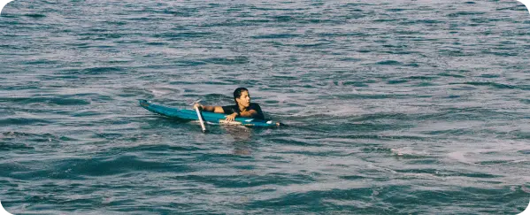 Josselyn Alabi remando sobre su tabla en el mar de El Salvador